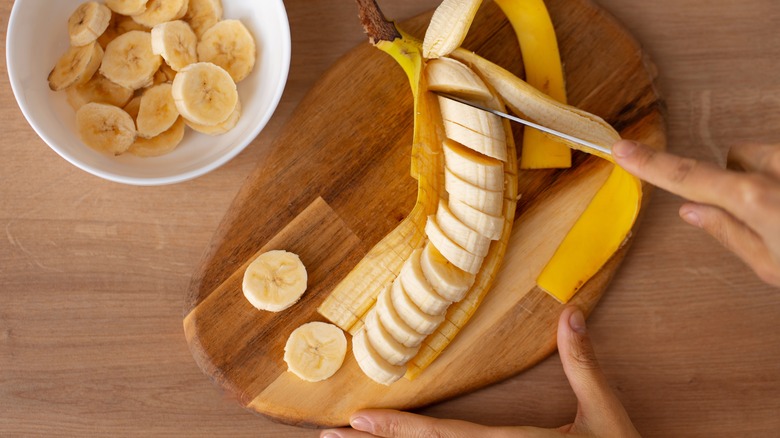 Person slicing banana in peel