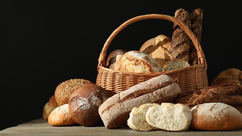 Several types of bakery loaves in a basket and on a table