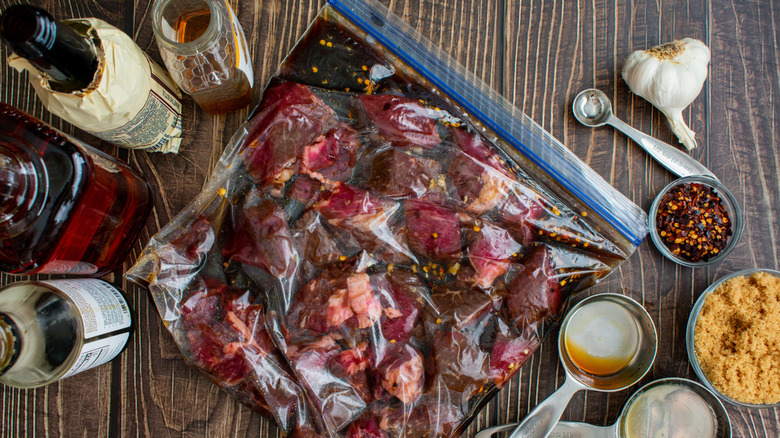 meat marinating in plastic bag surrounded by bottles and ingredients