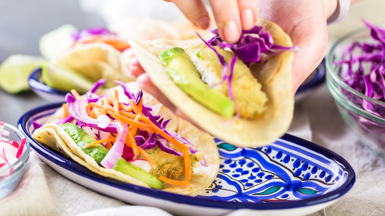 Hand putting ingredients in tacos