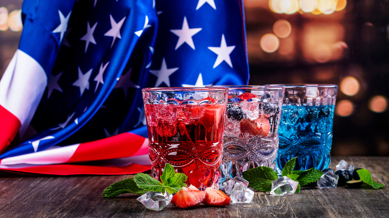 Three red, white, and blue shot glasses next to US flag