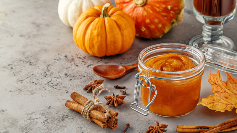 Jar of pumpkin butter with spices, pumpkins