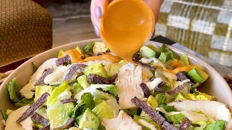 still of woman pouring dressing on salad