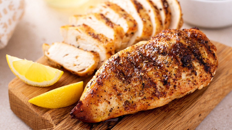 chicken breast on a wood board with lemon