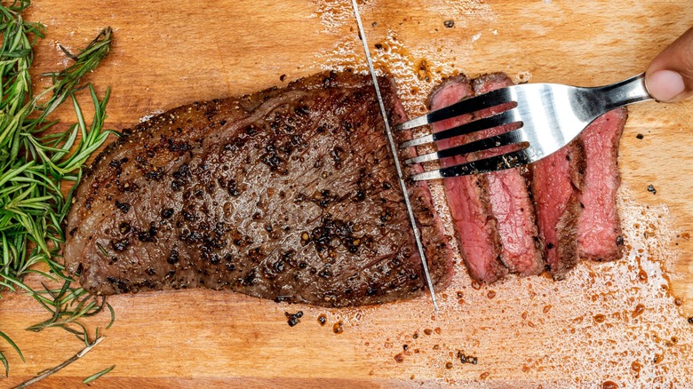 Knife and fork cutting cooked picanha steak