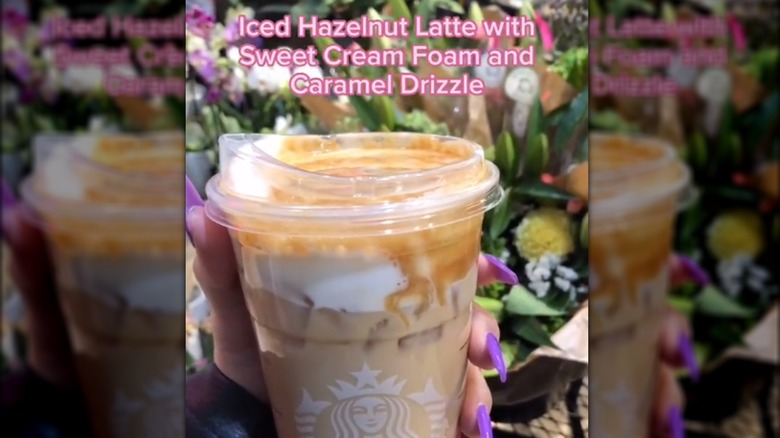 Hand holding Starbucks iced hazelnut latte