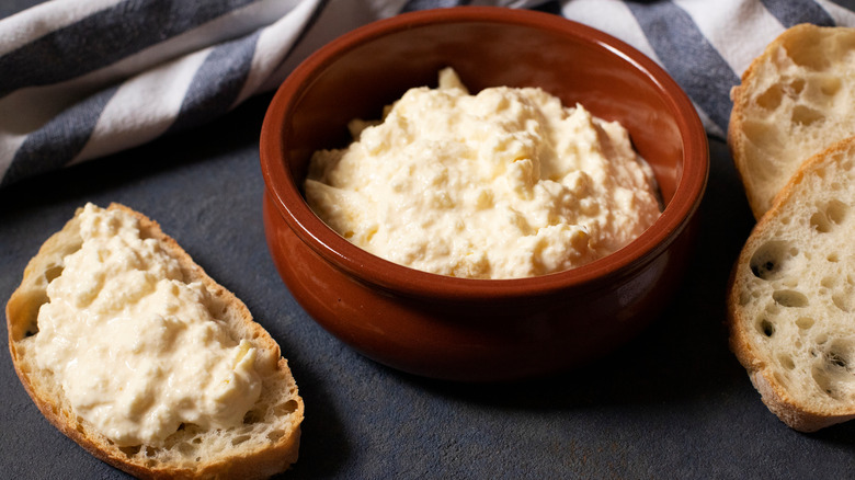 Bowl of kajmak and a slice of bread smeared with kajmak 