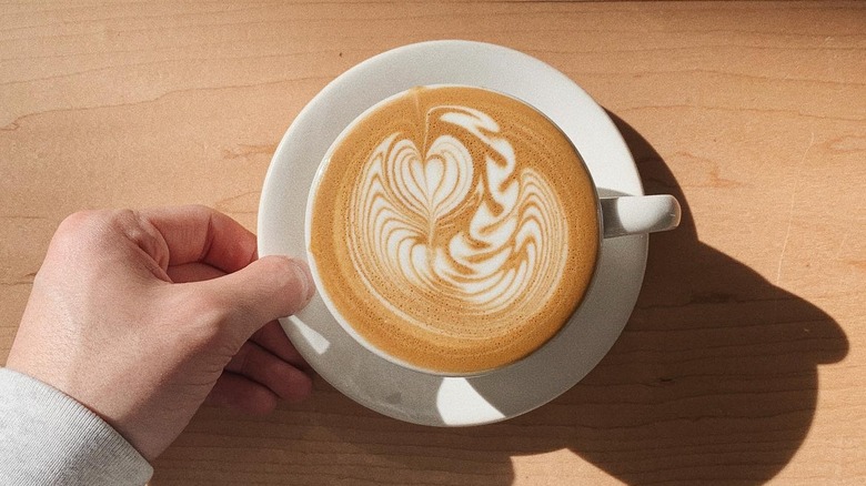 Hand placing latte in dish