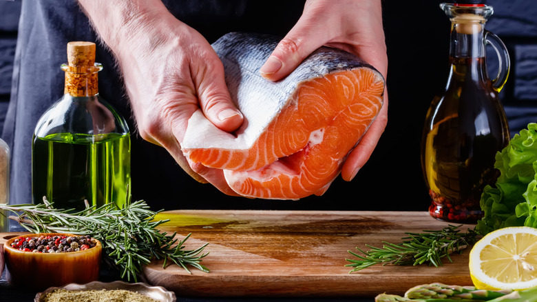 Hands clutching raw salmon portion