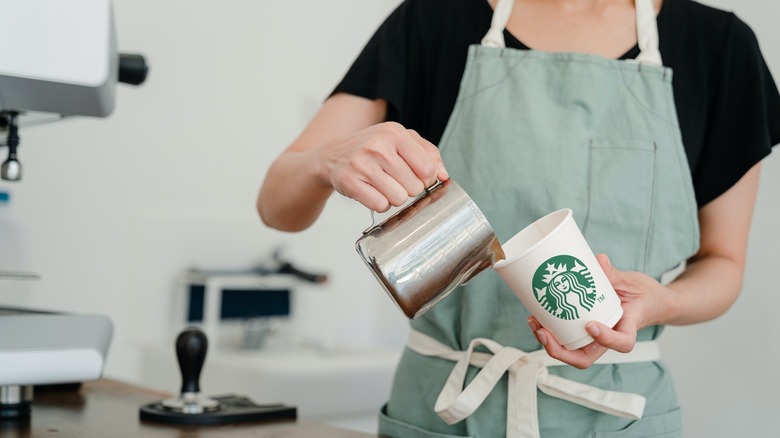 Barista pouring milk into cup