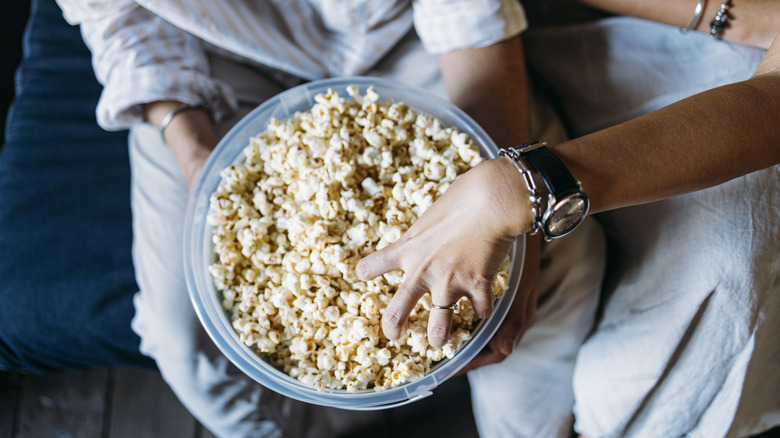 Hand reaching into popcorn bowl