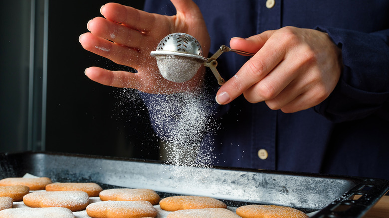 Baker dusting pastires with confectioner's sugar