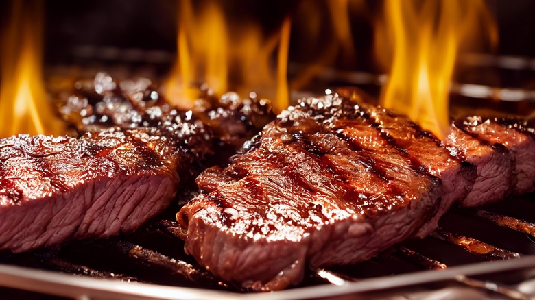 steaks grilling over a flame