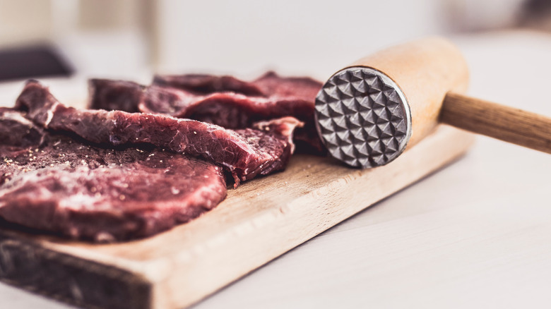 raw cube steak and meat mallet