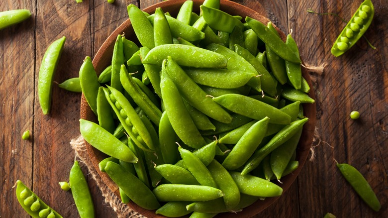Top-down views of raw snap peas in a bowl