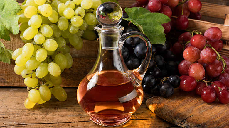 bottle of vinegar in front of fresh grapes