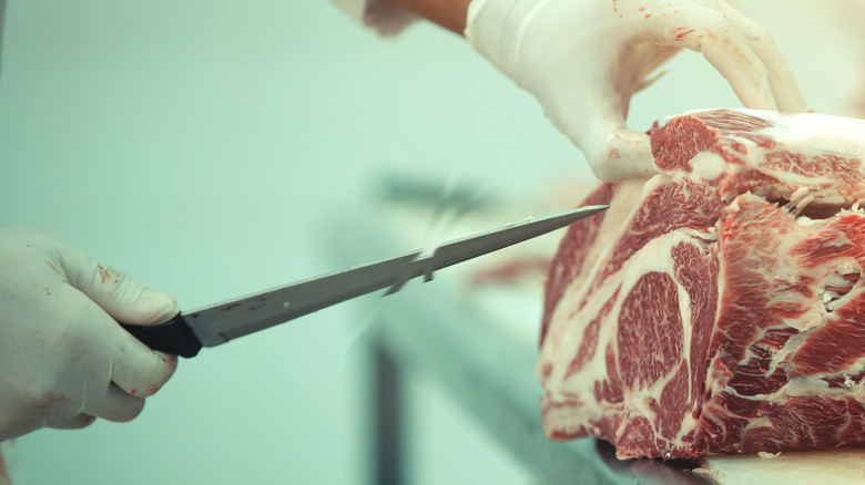 A chef cutting a block of meat