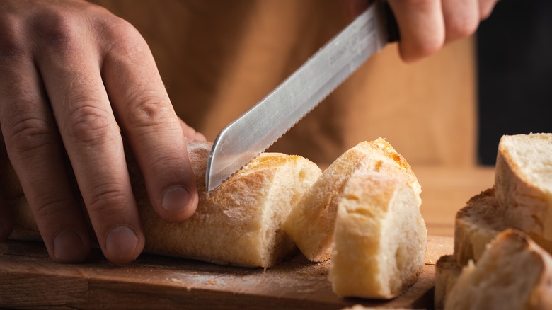 A chef cutting a loaf of bread