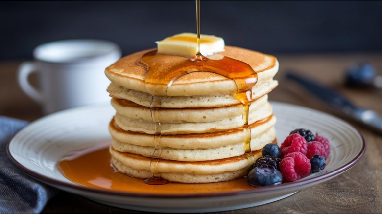 Golden maple syrup being poured on pancakes