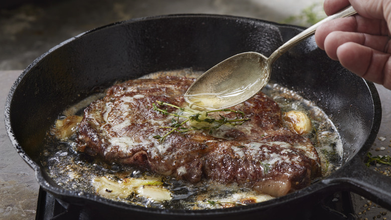 person basting steak with butter
