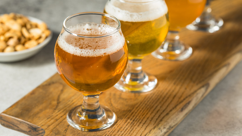 A flight of beer glasses on a wooden board