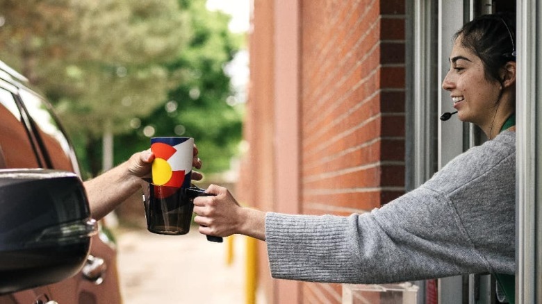 Barista handing drink to car