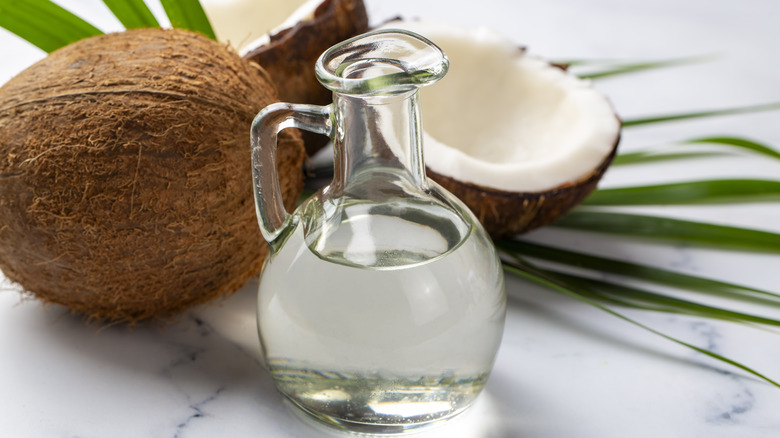 Bottle of coconuts with fresh coconut and palm leaves