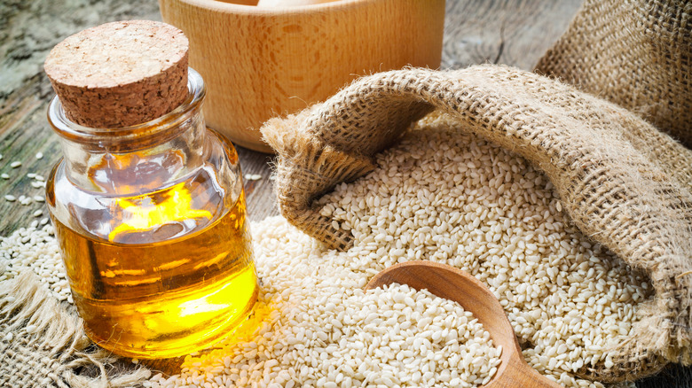 Sesame oil bottle beside sack of sesame seeds