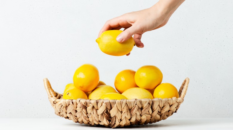 hand holding lemon in bowl