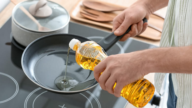 Person pouring oil in pan