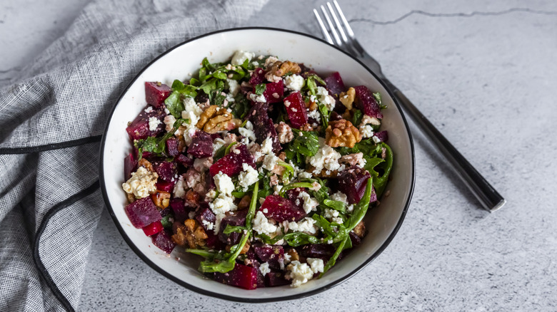 Beet salad in a bowl with walnuts, dried cranberries, and crumbled cheese