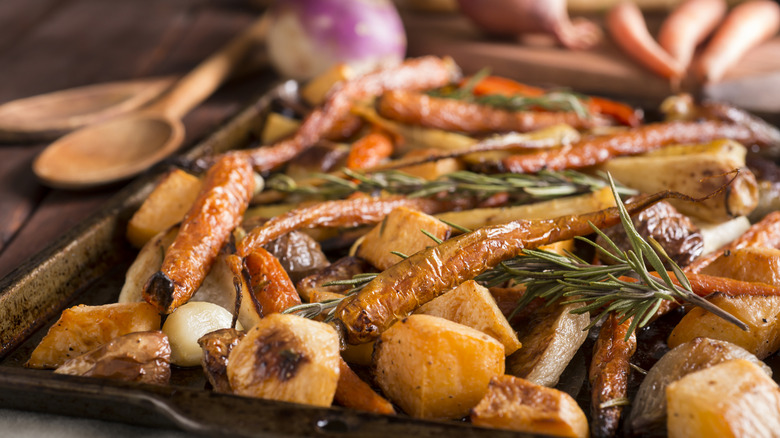 Roasted root vegetables on a tray with rosemary sprigs