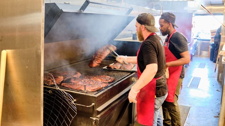 two men cooking ribs on grill