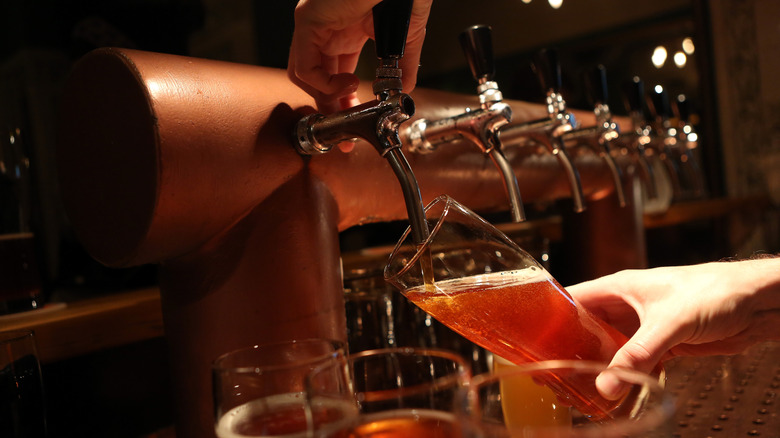 Bartender pours a draft of beer in a dark bar