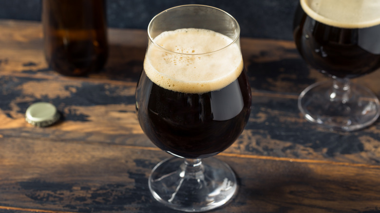 Dark beer in a small glass on a wooden table