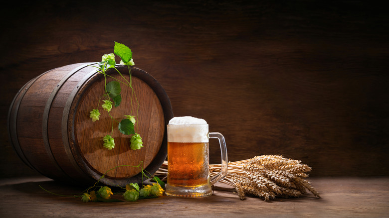 mug of beer, wheat ears, hops and beer barrel on a wooden background