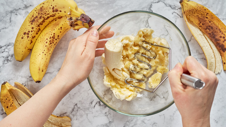 Person mashing bananas in bowl