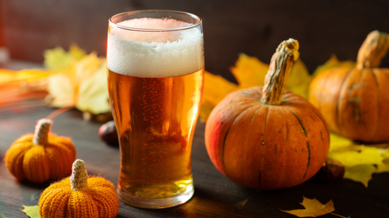 A beer surrounded by pumpkins.