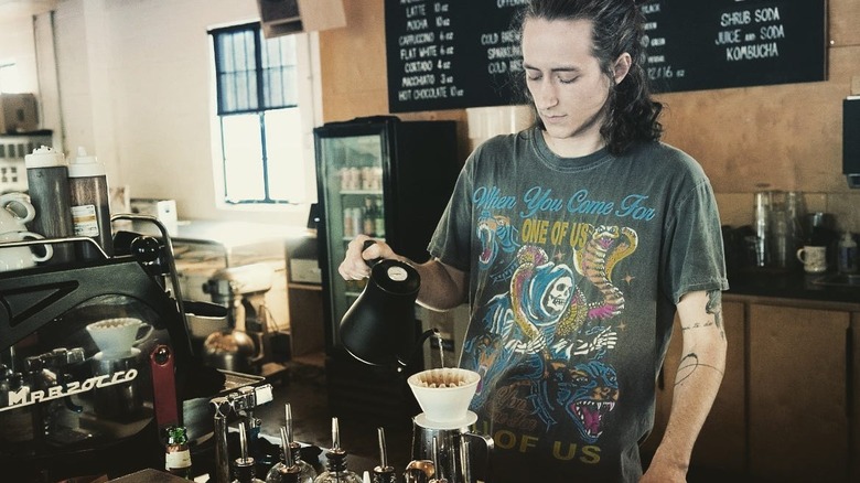 Barista pouring coffee through filter at counter