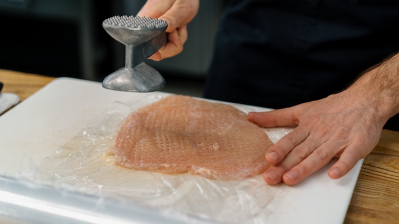 Pounding chicken with tenderizer