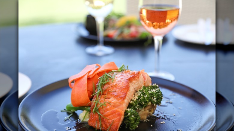 salmon on a plate alongside a glass of rosé wine