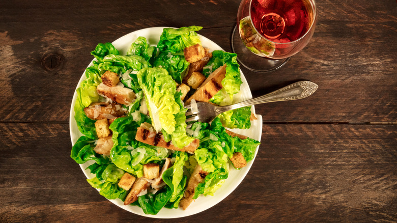 caesar salad with rosé on wood table