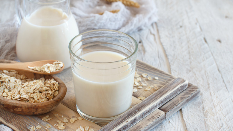 Oat milk in a glass with a bowl of oats