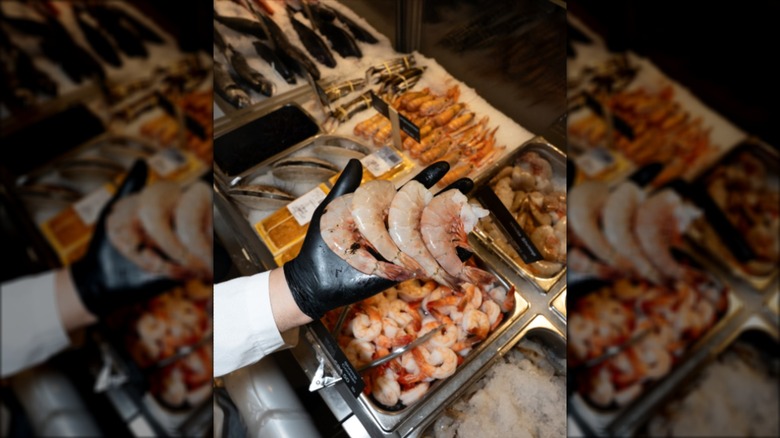 Hand holding jumbo shrimp over the counter at Lobster Place
