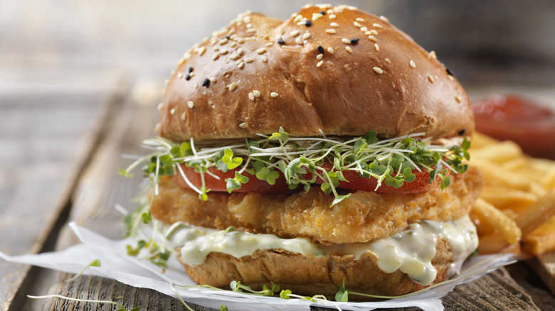 A fried fish sandwich with micro-verts and tartare sauce on a seed bread