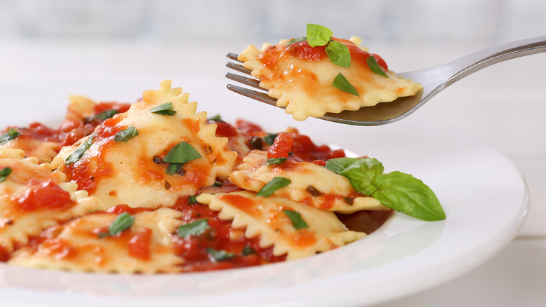 Eating ravioli and tomato sauce with basil