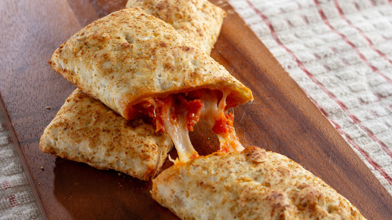 a hot pocket sliced in half oozing cheese and red sauce