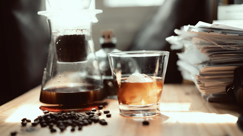 Pour-over cold brew coffee alongside a glass of bourbon