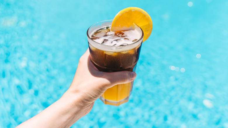 Orange espresso with slice of orange on blue swimming pool background