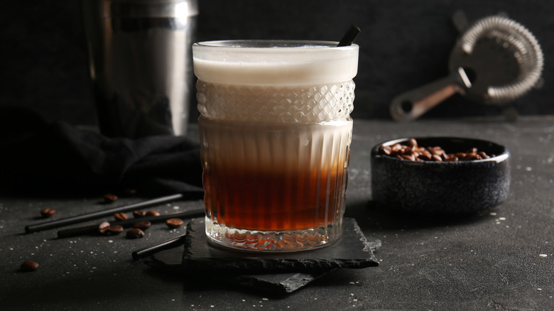 White Russian cocktail with coffee beans in the background